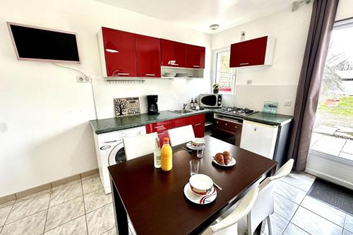 a kitchen with red cabinets and a wooden table at Les Roses-Plain-pied-St Valery & Le Crotoy à 10min in Noyelles-sur-Mer