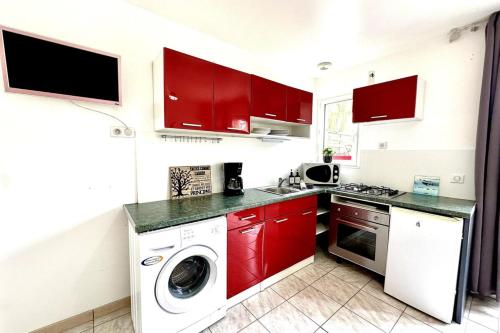 a kitchen with red cabinets and a washer and dryer at Les Roses-Plain-pied-St Valery & Le Crotoy à 10min in Noyelles-sur-Mer