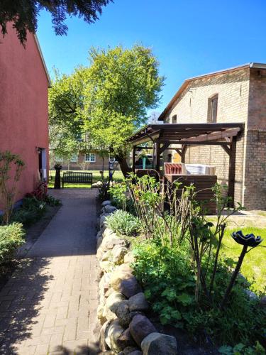 a garden with a bench and a wooden pergola at Pension Stocker in Dierhagen