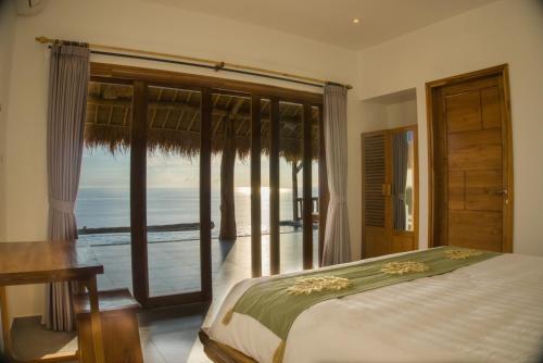 a bedroom with a bed and a view of the ocean at Angsoka Villas Amed in Amed