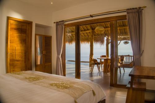 a bedroom with a bed and a view of the ocean at Angsoka Villas Amed in Amed
