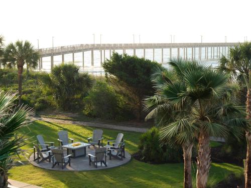 a table and chairs in a garden with a bridge in the background at DoubleTree Resort by Hilton Myrtle Beach Oceanfront in Myrtle Beach