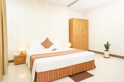 a white bedroom with a large bed and a cabinet at Viet Thai Hotel in Hồng Lĩnh