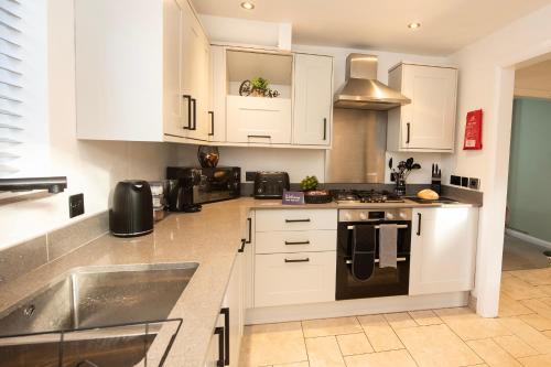 a kitchen with white cabinets and a sink at Stylish 4 Bed House, Free Parking, Close to M4 Newport in Newport