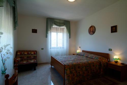 1 dormitorio con 1 cama, 1 silla y 1 ventana en Agriturismo La Vecchia Fontana, en Penne