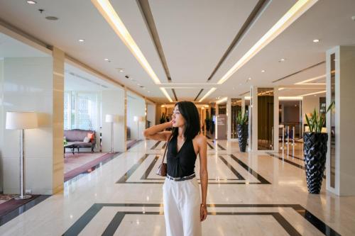 a woman in a lobby talking on a cell phone at Mandarin Hotel Managed by Centre Point in Bangkok