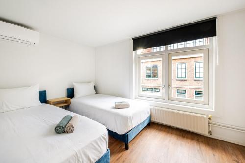 a bedroom with two beds and a window at The Alkmaar Family House in Alkmaar