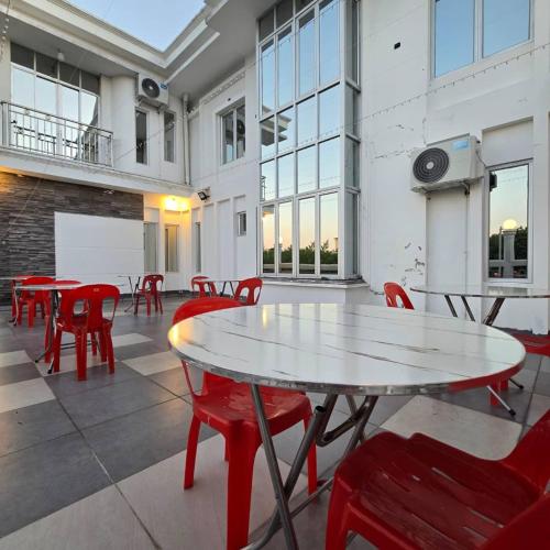 una stanza con tavoli e sedie rosse in un edificio di Magnificent White House Semporna by The Minimalist a Semporna