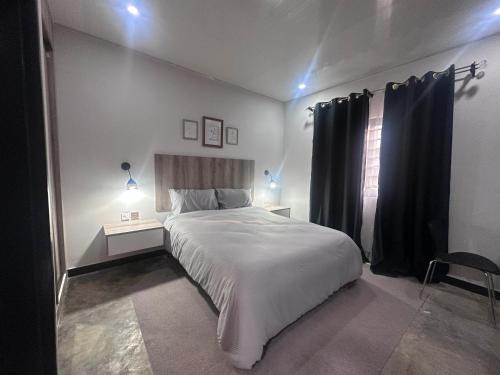 a bedroom with a large white bed and a window at Zango Apartments in Shikalenge