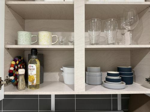 ein Küchenregal mit Geschirr und Weingläsern in der Unterkunft Shine Stay 5 Min from Songdo Moonlit Festiv Park Station in Taeam