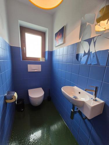 a blue tiled bathroom with a toilet and a sink at Big Garden House in Feldkirch