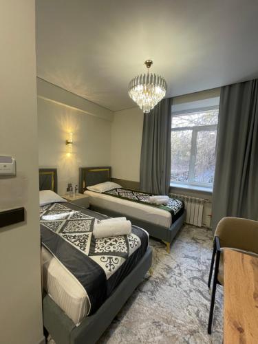a bedroom with two beds and a chandelier at Naya Hotel in Almaty