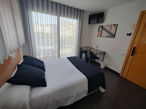 a bedroom with a bed and a window with a desk at Hostal Manel in Pineda de Mar