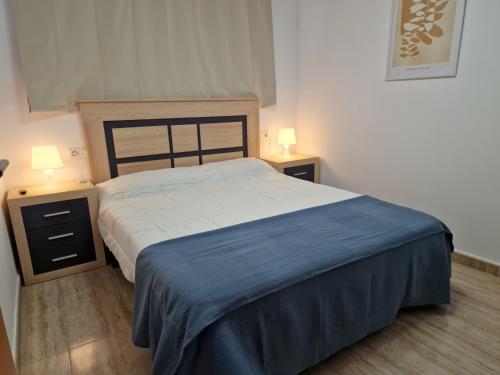a bedroom with a large bed and two night stands at APCOSTAS Palmavera Playa de la Conxa in Oropesa del Mar