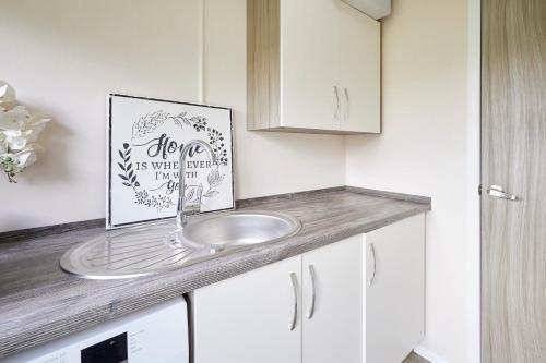 une salle de bain avec un lavabo et un tableau sur le comptoir dans l'établissement Reynards Retreat Lodge with Hot Tub, à Barmby on the Moor