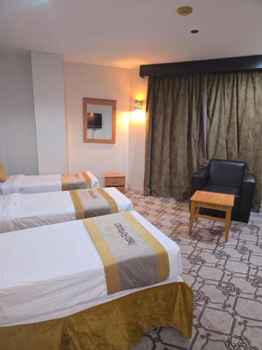 a hotel room with two beds and a chair at برج الجوار السكني أجياد المصافي Jiwar Tower Ajyad Al Masafi in Al Gharīth