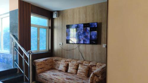 a living room with a couch and a television on a wall at Green View in Mussoorie