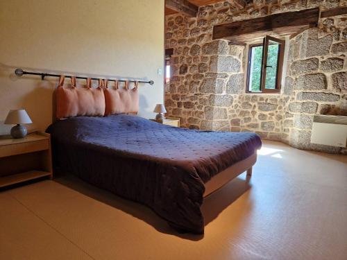 a bedroom with a bed and a stone wall at Gîte de la Capelle in Touluch