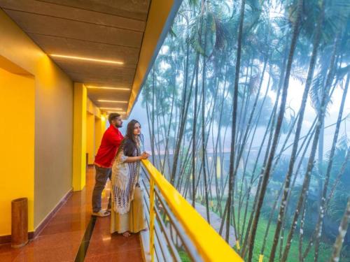 um homem e uma mulher em pé em uma varanda com vista em The Hosteller Wayanad, Vythiri em Vythiri