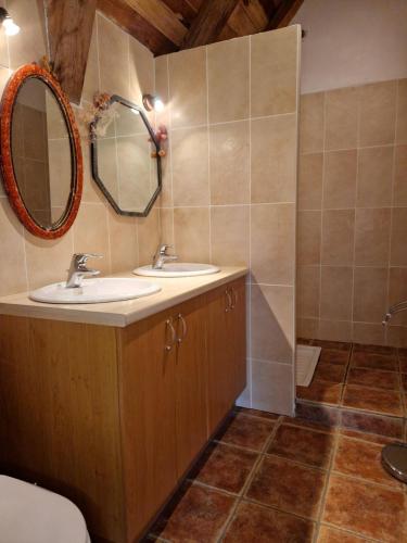 a bathroom with two sinks and a mirror at La Fontaine d'Aubrac in Florentin-la-Capelle