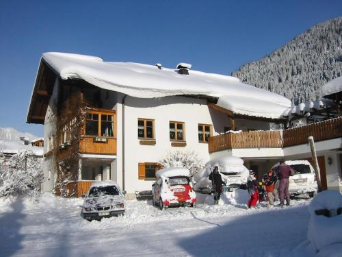 Una casa cubierta de nieve con coches aparcados fuera de ella. en Ruhige Wohnung Im Ortszentrum, en Sankt Gallenkirch