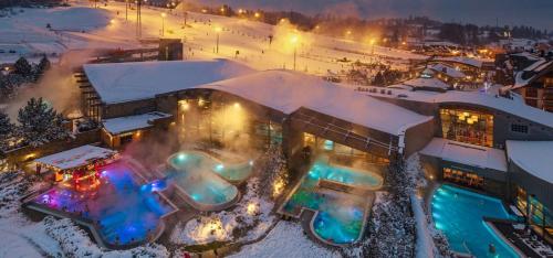 a building with a pool in the snow at night at DWOREK MYŚLIWSKI HUBERT-Tutaj czeka na ciebie oszczędność & komfort & najlepsza lokalizacja, Jesteśmy przy samych Termach Bania i Stoku Narciarskiego Kotelnica, Na miejscu wypożyczalnia nart, rowerów w atrakcyjnej cenie dla gości oraz darmowy parking in Białka Tatrzańska