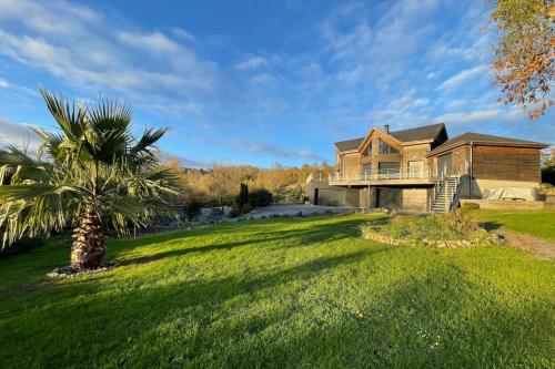 a large house with a palm tree in the yard at Le Clos des Cigognes - Architect-designed house near Omaha Beach in Trévières