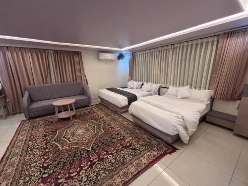 a hotel room with two beds and a couch and a rug at NR Hotel in Rīngas