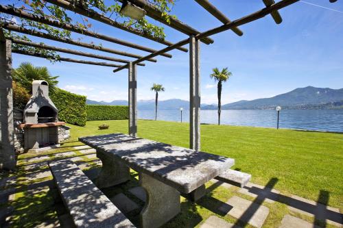 a stone bench sitting under a pergola next to the water at Yachting Residence in Ghiffa