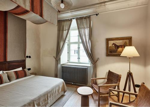 a bedroom with a bed and a chair and a window at Zámek Žďár in Žďár nad Sázavou