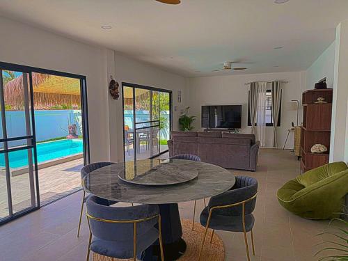 a living room with a table and chairs and a pool at Villa l'Aurora in Amphoe Koh Samui