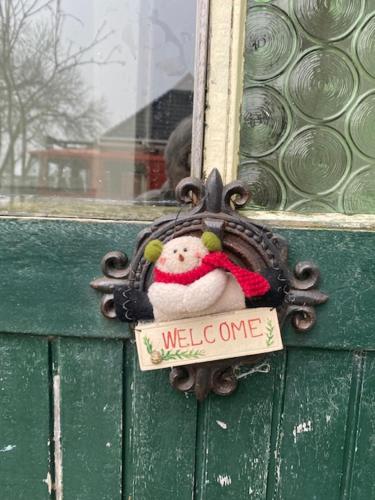 a teddy bear with a welcome one sign on a door at Achter de kerk in Eppenhuizen