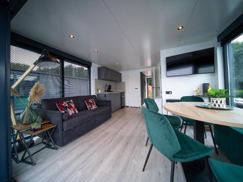 a living room and kitchen with a couch and a table at Houseboat Marina Mookerplas 4-6 persoons (met hottub en dakterras) in Middelaar