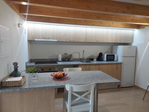 a kitchen with a table and a counter with a bowl of fruit at Casa da Fraga in Viana do Castelo