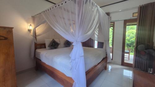 a bedroom with a canopy bed with white curtains at Sugi Gede Homestay in Singaraja