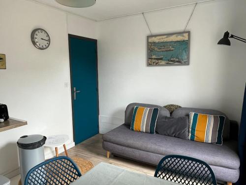 ein Wohnzimmer mit einer Couch und einer Uhr an der Wand in der Unterkunft Appartement T2, très bien équipé, avec terrasse, jardin, et accès piscine in Cambo-les-Bains