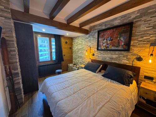 a bedroom with a large bed and a brick wall at Immodelpas Pic Blanc in Pas de la Casa