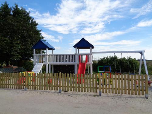 a playground behind a wooden fence with a play equipment at Marijanas Ferienhof 1, Urlaub mit viel Platz zwischen Dornumersiel und Bensersiel, gehört zum Café Kunterbunt in Middelsbur