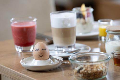 Una mesa con un huevo en un plato con una cuchara. en Hotel Konradshof, en Seewald