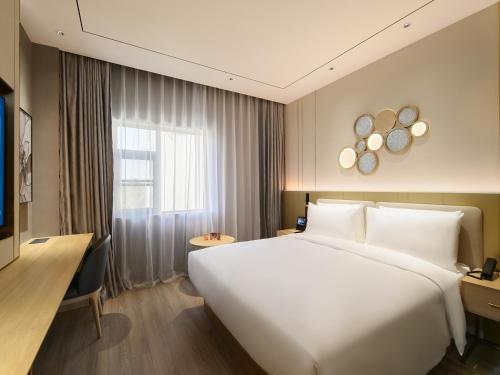 ein Schlafzimmer mit einem großen weißen Bett und einem Fenster in der Unterkunft Orange Hotel Shanghai New International Expo Centre in Shanghai