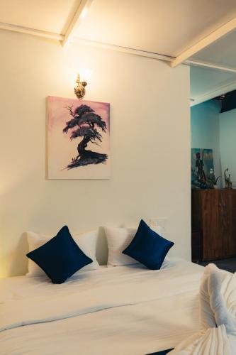 a bedroom with a white bed with blue pillows at Coorg Saturn Homes in Madikeri