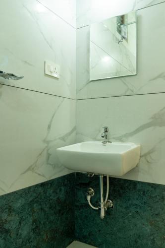 a white bathroom with a sink and a mirror at Coorg Saturn Homes in Madikeri