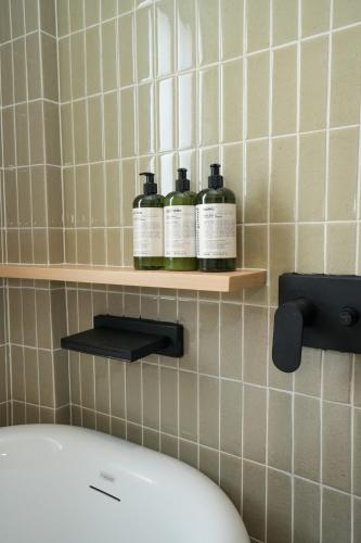 a bathroom with two bottles on a shelf above a toilet at day one space - BTS On Nut - Live Above Cowork Cafe in Bangkok