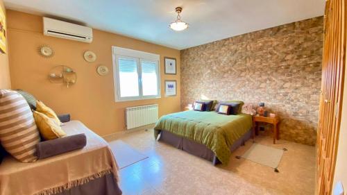 a bedroom with two beds and a stone wall at Casa Julieta, tu hogar en Toledo, ideal Puy du Fou in Bargas
