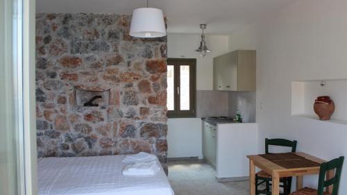a bedroom with a stone wall with a bed and a table at Dimitra Studios in Aegiali