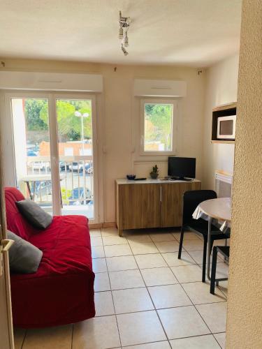 a living room with a red couch and a table at Le petit soleil in Lamalou-les-Bains