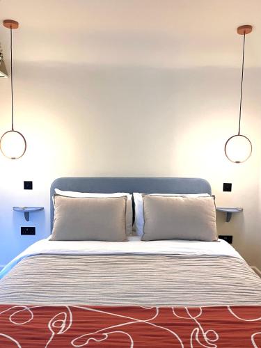 two lights above a bed with two pillows at Cosy Studio Steps From Beach in Weymouth