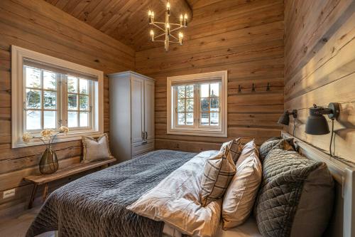 1 dormitorio con 1 cama con paredes y ventanas de madera en Tømmerhytte Ved Historiske Senhovd, en Veggli