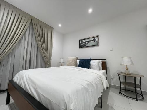 阿克拉The Bantree D-plus Apartments的白色卧室配有一张大床和一张桌子