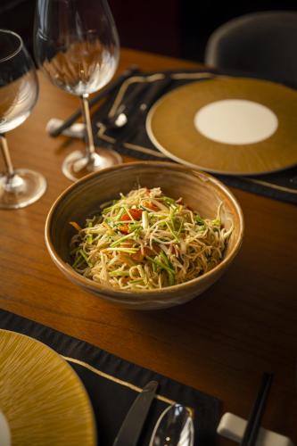 uma tigela de comida numa mesa com copos de vinho em Taj Ganga Kutir Resort & Spa, Raichak em Raichak